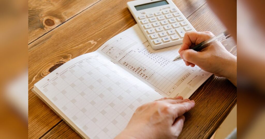 家計簿をつけている手